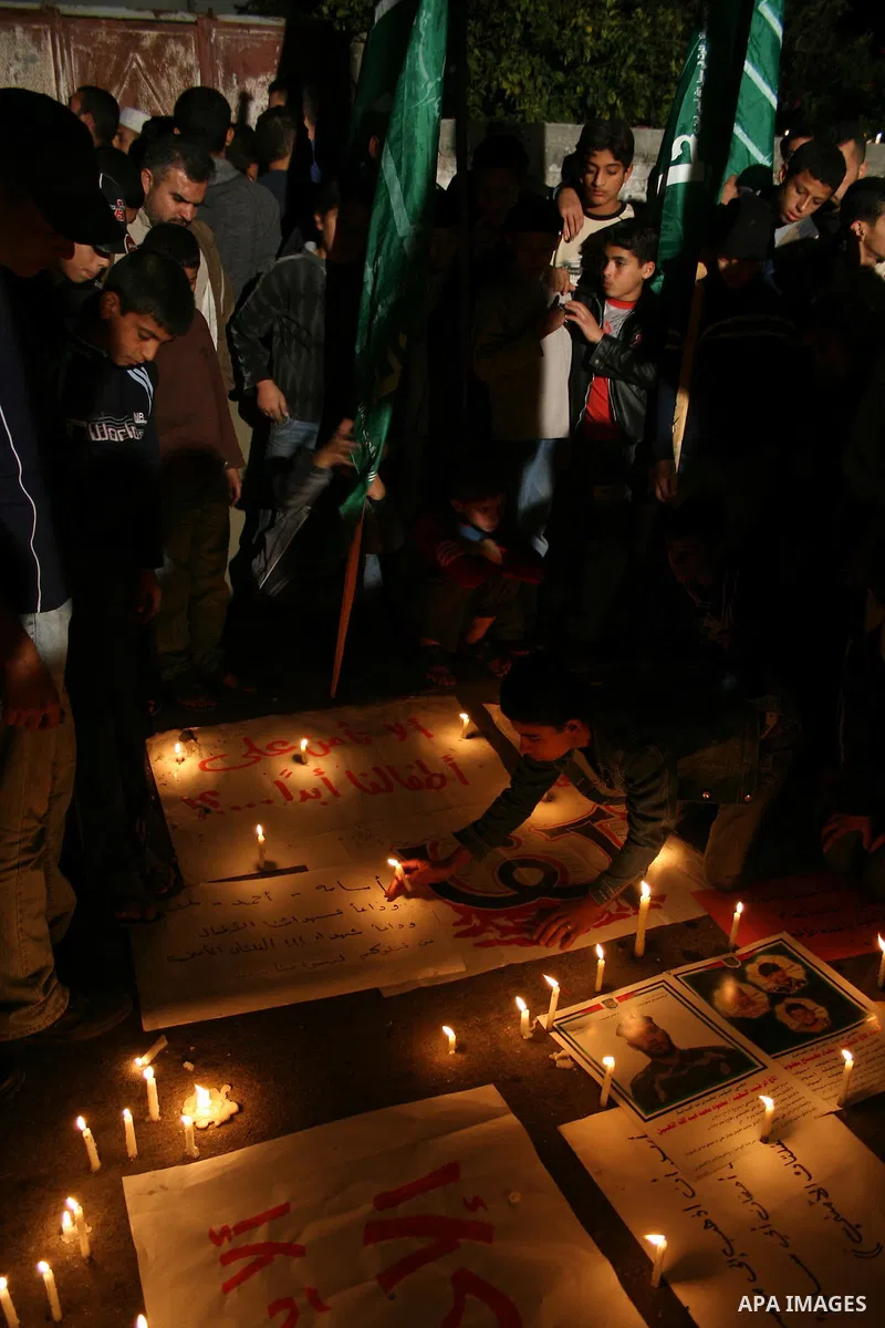 Palestinian children burn candles after killing three Palestinian boys, Salam, 6-years-old, Ahmed, 7-years-old, and Ossama, 8, the three sons of Palestinian intelligence chief Bahaa Baalush in Gaza City. The three young...