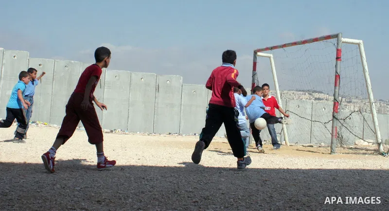 palestinian students play football in playground after they come back from their school next the separation wall near the west bank village of anabta.
