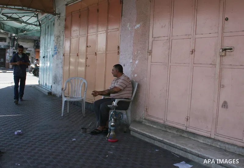 A Palestinian shopkeeper sits outside closed shops during a general strike called by supporters of the Fatah Movement in the West Bank. Activists in the Fatah movement declared a general strike across the Gaza Strip and...
