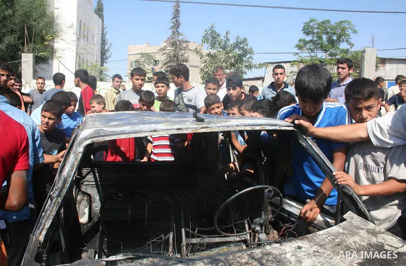 Palestinian gather around the car after an Israeli air strike in Jabaliya refugee camp, northern Gaza strip. ..Two Palestinian militants from the radical Islamic Jihad group were wounded in an Israeli air strike against...