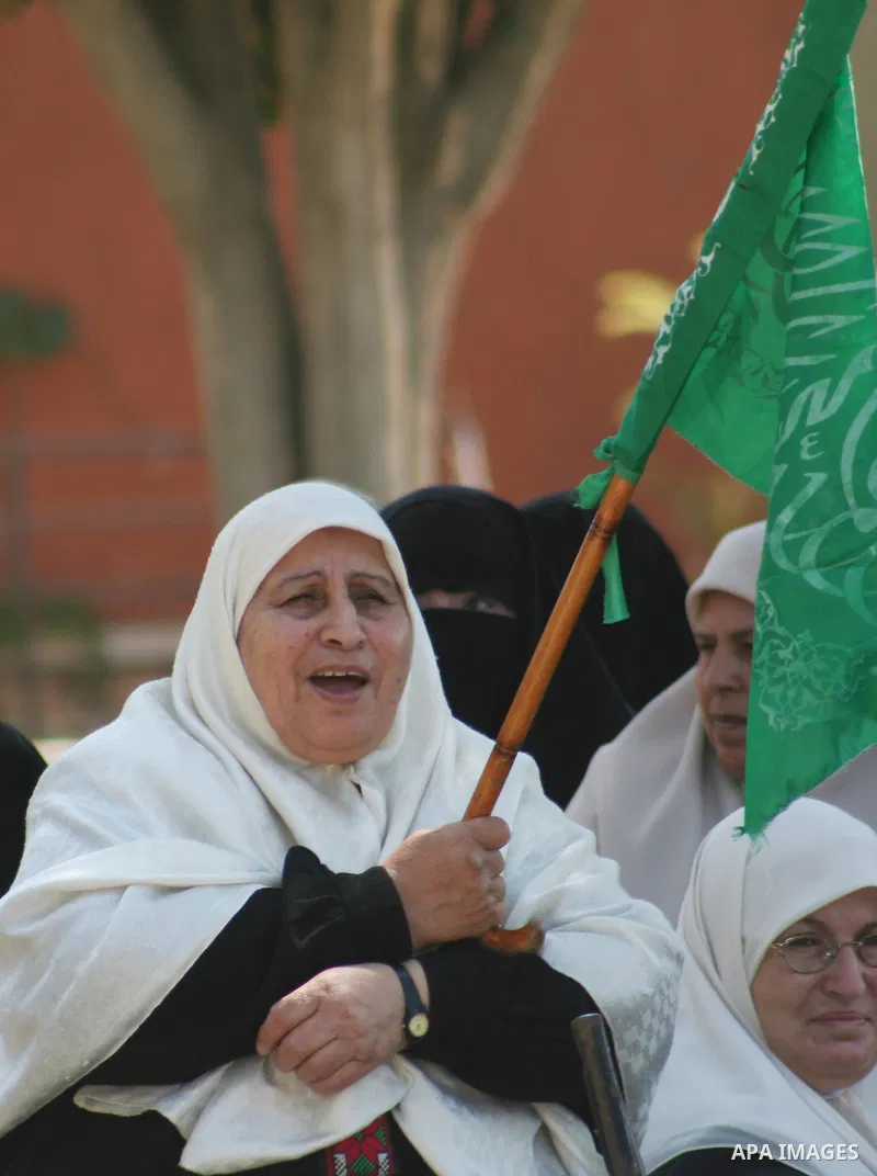 A Palestinian elderly woman supporter of the Hamas movement holds a banner during a demonstration in front of the legislative council in Gaza City. Palestinian women demanding to halt the palestinian authority forces's v...