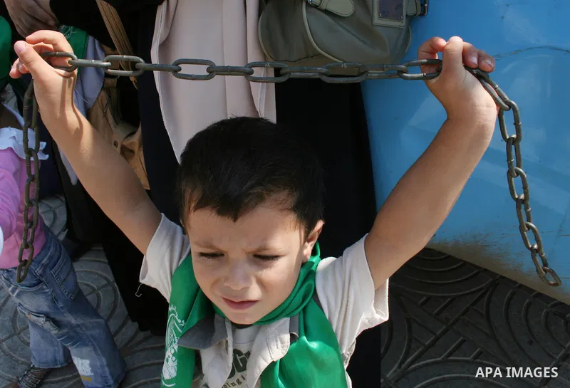 A Palestinian child holds iron restrictions and stands with palestinian women supporters of the Hamas movement gather during a demonstration in front of the legislative council in Gaza City. Palestinian women demanding t...