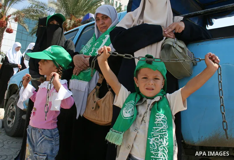 A two Palestinian children hold iron restrictions and stand with palestinian women supporters of the Hamas movement gather during a demonstration in front of the legislative council in Gaza City. Palestinian women demand...