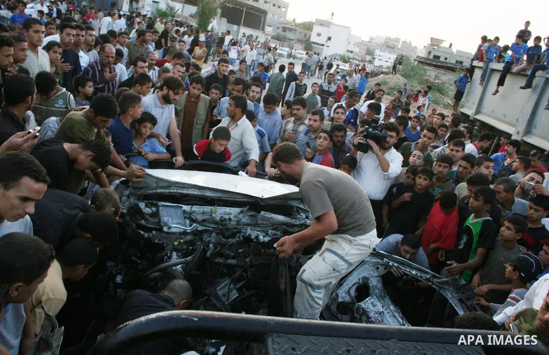 Palestinians gather around the wreckage of militants car after it was hit in an Israeli missile strike in the Zeitoun area in the east of Gaza City. Four Palestinian militants were killed in the strike.