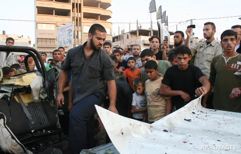 Palestinians gather around the wreckage of militants car after it was hit in an Israeli missile strike in the Zeitoun area in the east of Gaza City. Four Palestinian militants were killed in the strike.