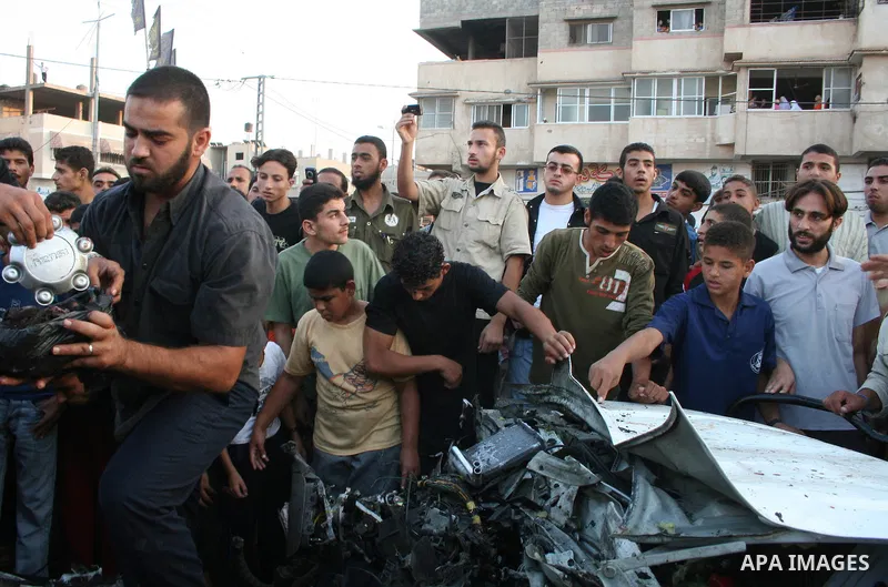 Palestinians gather around the wreckage of militants car after it was hit in an Israeli missile strike in the Zeitoun area in the east of Gaza City. Four Palestinian militants were killed in the strike.