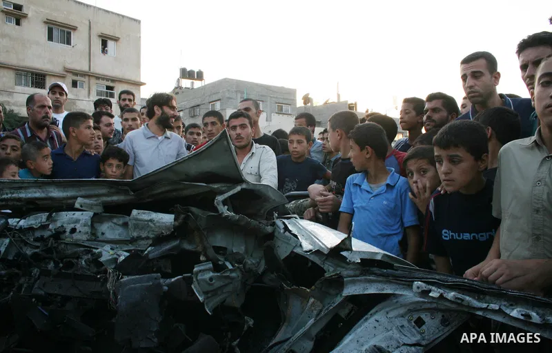 Palestinians gather around the wreckage of militants car after it was hit in an Israeli missile strike in the Zeitoun area in the east of Gaza City. Four Palestinian militants were killed in the strike.
