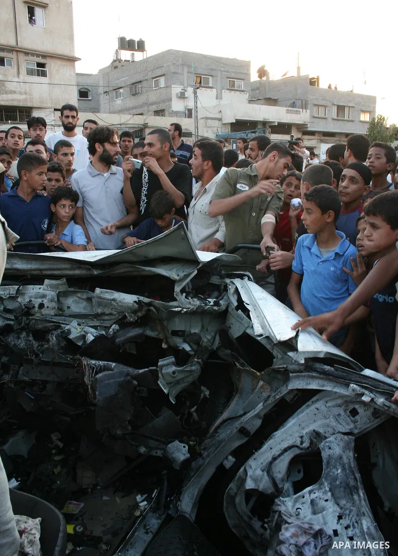 Palestinians gather around the wreckage of militants car after it was hit in an Israeli missile strike in the Zeitoun area in the east of Gaza City. Four Palestinian militants were killed in the strike.