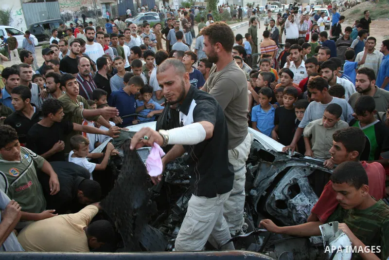 Palestinians gather around the wreckage of militants car after it was hit in an Israeli missile strike in the Zeitoun area in the east of Gaza City. Four Palestinian militants were killed in the strike.