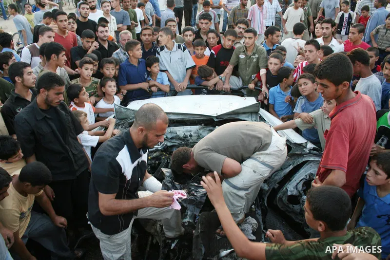 Palestinians gather around the wreckage of militants car after it was hit in an Israeli missile strike in the Zeitoun area in the east of Gaza City. Four Palestinian militants were killed in the strike.