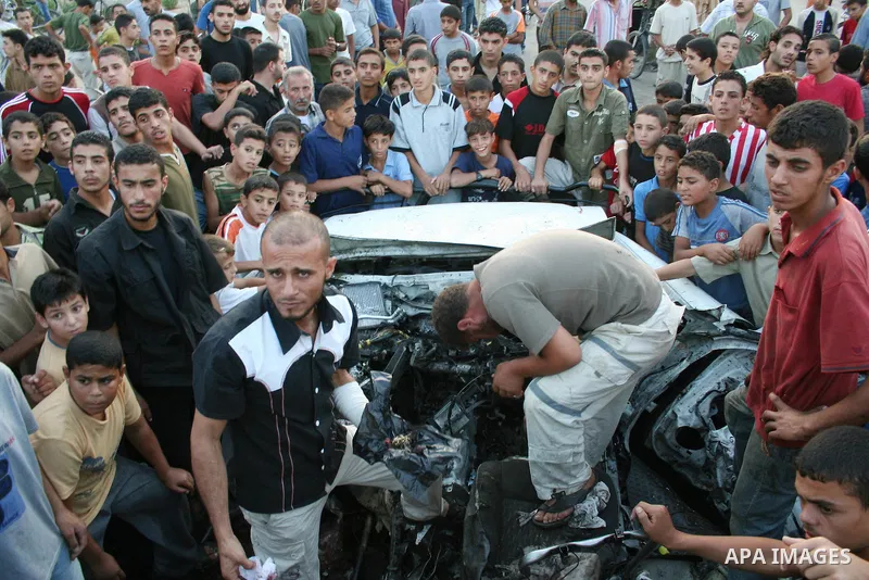 Palestinians gather around the wreckage of militants car after it was hit in an Israeli missile strike in the Zeitoun area in the east of Gaza City. Four Palestinian militants were killed in the strike.