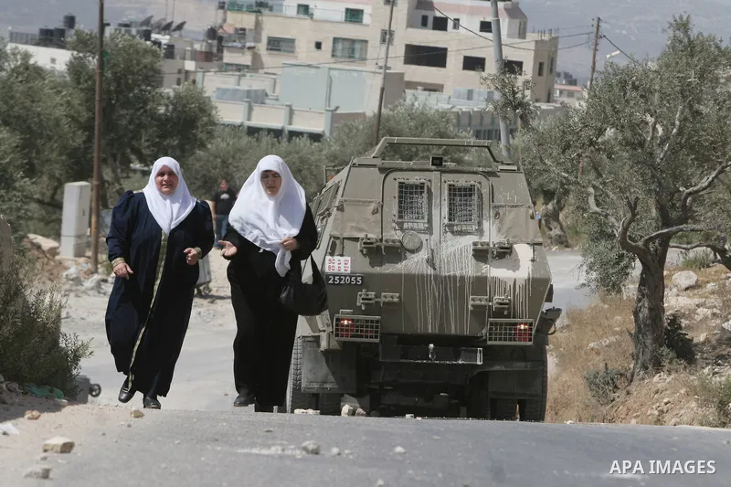 Palestinian women walk forward Israeli troops raiding the West Bank town of Nablus. A Palestinian boy was wounded during the clashes, hospital sources said.