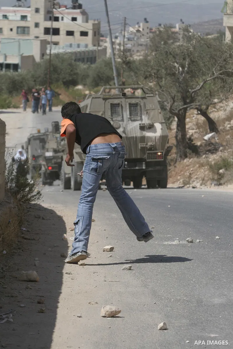 Palestinian youth hurling stones at Israeli troops raiding the West Bank town of Nablus. A Palestinian boy was wounded during the clashes, hospital sources said.