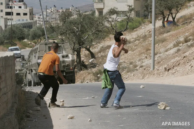 Palestinian youth hurling stones at Israeli troops raiding the West Bank town of Nablus. A Palestinian boy was wounded during the clashes, hospital sources said.