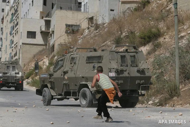 Palestinian youth hurling stones at Israeli troops raiding the West Bank town of Nablus. A Palestinian boy was wounded during the clashes, hospital sources said.