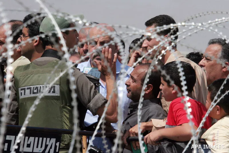 Palestinian worshippers wait at the West Bank Qalandiya Israeli manned checkpoint, now integrated into the controversial separation barrier (behind) being built by Israel , as they hope to cross and make their way to Jer...