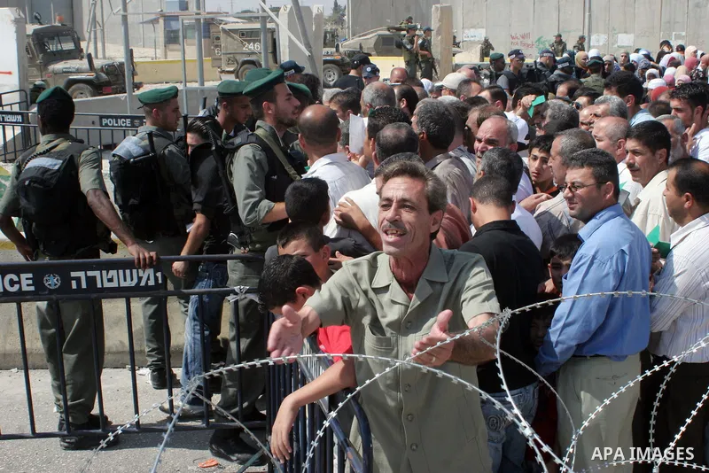 Palestinian worshippers wait at the West Bank Qalandiya Israeli manned checkpoint, now integrated into the controversial separation barrier (behind) being built by Israel , as they hope to cross and make their way to Jer...