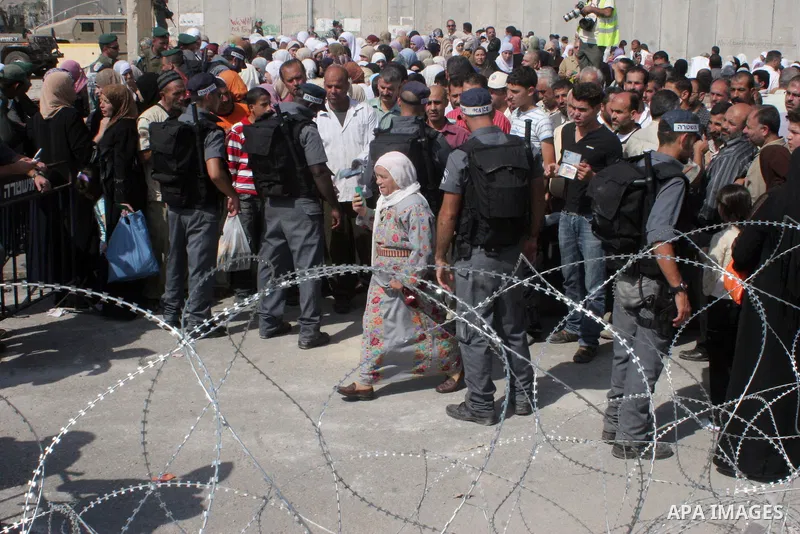 Palestinian worshippers wait at the West Bank Qalandiya Israeli manned checkpoint, now integrated into the controversial separation barrier (behind) being built by Israel , as they hope to cross and make their way to Jer...