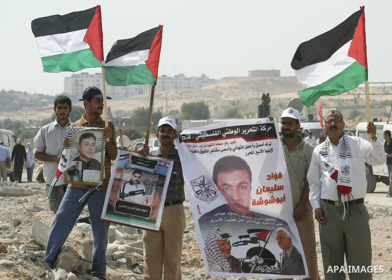 Palestinian men hold up the national flags as they welcome back prisoners released from Israeli prisons at the Erez checkpoint in the northern Gaza Strip. Israel sent 29 Palestinian prisoners back to the Gaza Strip on Tu...