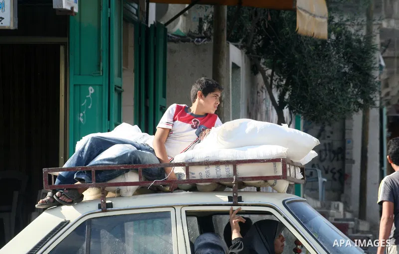 Palestinian boy are seen up the roof of the car with the bucket of flour after he receives from UNRWA center in al-Shati refugee camp in Gaza city.