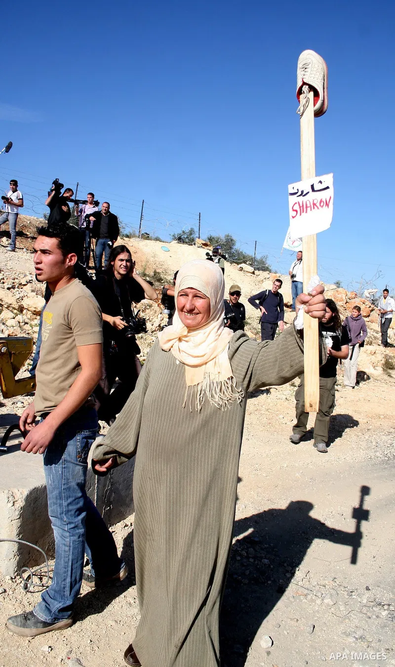 Palestinian demonstrators holds up shoes and a placards bearing the portrait of US President George W. Bush during a protest against Israel's separation barrier and in solidarity with Iraqi journalist Muntazar al-Zaidi,...