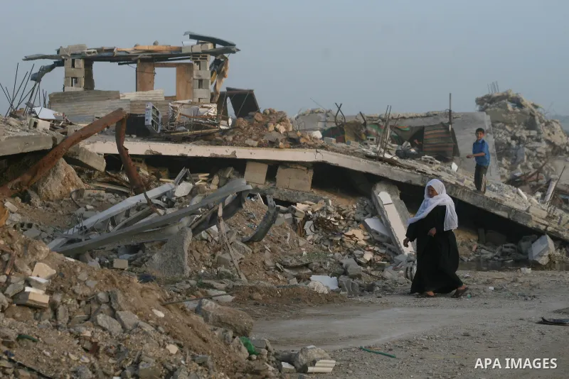A Palestinian woman walks past a house destroyed during Israel's 22-day offensive in Jabalia in the northern Gaza Strip on February 16, 2009. Israeli aircraft struck smuggling tunnels on Gaza's border with Egypt, after t...