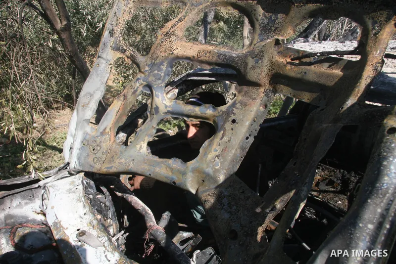 Palestinians inspect a destroyed car following an Israeli air strike in the central Gaza Strip refugee camp of Maghazi on February 23, 2009. The Israeli army carried out an air raid in the central Gaza Strip after a mili...