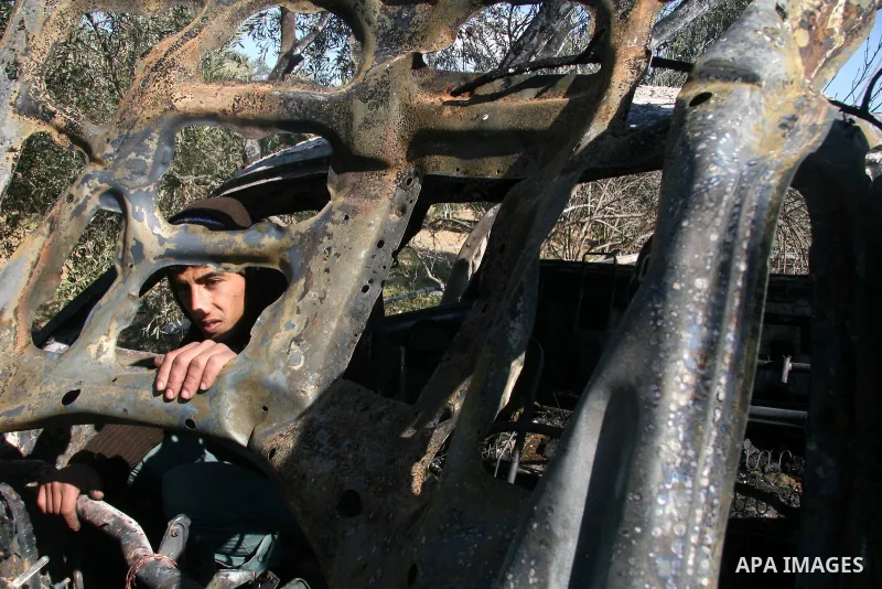 Palestinians inspect a destroyed car following an Israeli air strike in the central Gaza Strip refugee camp of Maghazi on February 23, 2009. The Israeli army carried out an air raid in the central Gaza Strip after a mili...