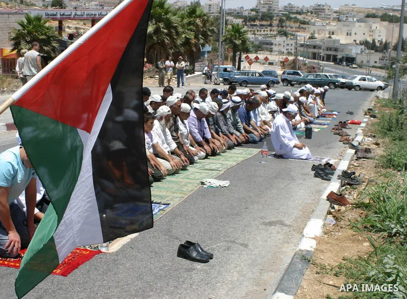 Palestinians pray in front of Israeli soldiers (not seen) during a protest against the construction of the controversial separation barrier in the village of Al-Khader near the West Bank city of Bethlehem.