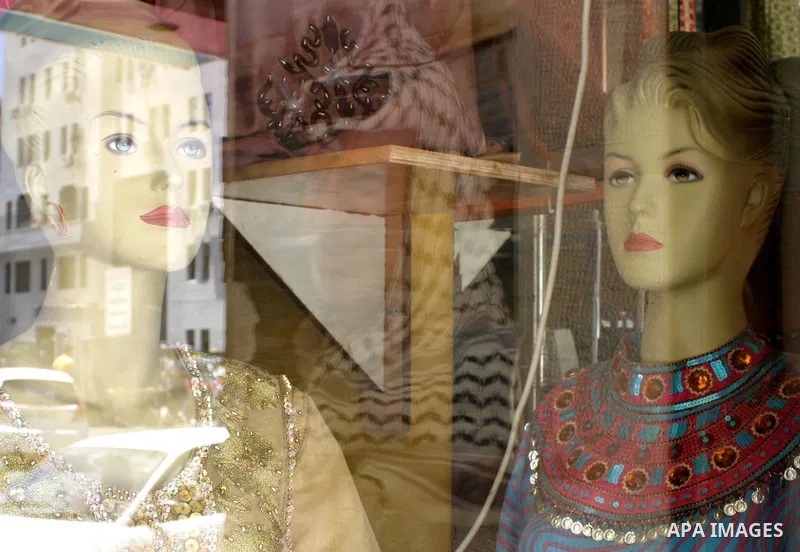 A picture of former Palestinian president Yasser Arafat is reflected between mannequin dolls in a shop window in Ramallah.