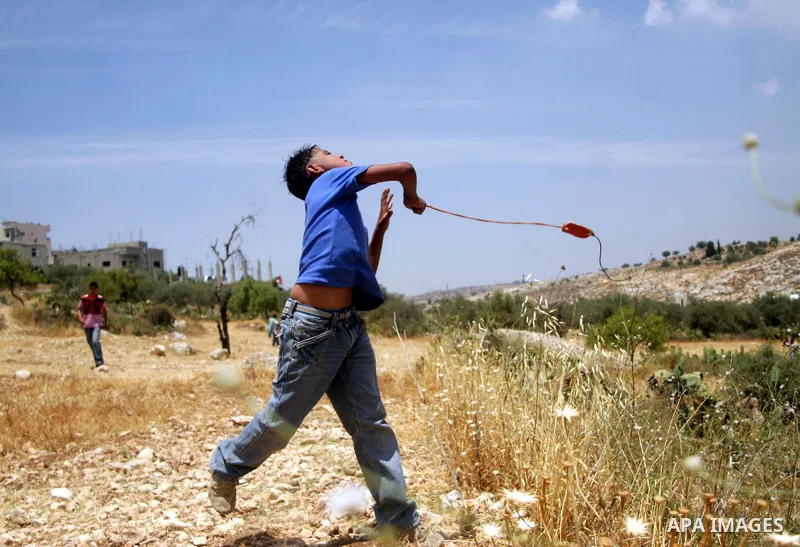 A Palestinian boy hurls a stone at Israeli soldiers during a demonstration against Israel's controversial separation barrier in the West Bank village of Nilin, near Ramallah. Five Palestinians were wounded today as Israe...