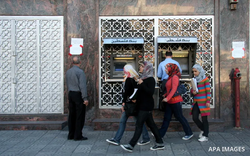 Palestinians stand in front of closed doors of Palestine in Gaza City. Banks in the Gaza Strip closed their branches today due to lack of liquidity and Israel's refusal to authorise cash transfers to the besieged territo...
