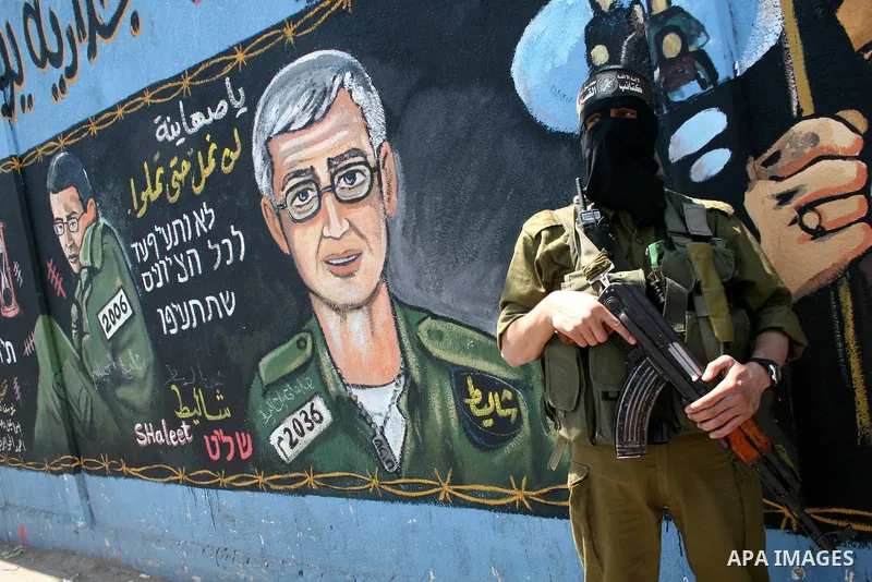 Hamas militantes stand nexta paint a mural depicting captured Israeli soldier Gilad Shalit during a rally demanding the release of Palestinian prisoners from Israeli jails in the Jablia refugee camp, northern Gaza Strip,...