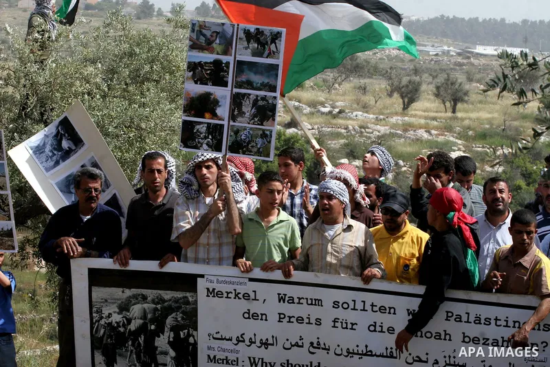 Palestinian demonstrators holding a banner depicting a famous photo of a Jewish boy during the Holocaust, in the West Bank village of Nilin, near Ramallah,thursday, April 21, 2009. .APAIMAGES PHOTO /Issam Rimawi