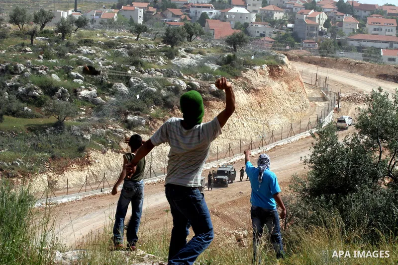 Palestinian youth hurls a stone at Israeli border policemen during a demonstration against Israel's separation barrier in the West Bank village of Nilin near Ramallah, thursday, April 21, 2009. .APAIMAGES PHOTO /Issam Ri...