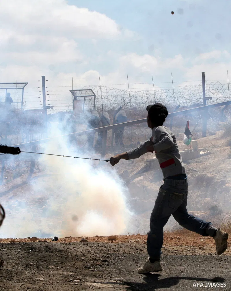 Palestinian demonstrator uses a sling-shot as he prepares to hurl a rock at Israeli troops during a protest against Israel's separation barrier in the West Bank village of Bilin near Ramallah, Friday, May 1, 2009.APAIMAG...
