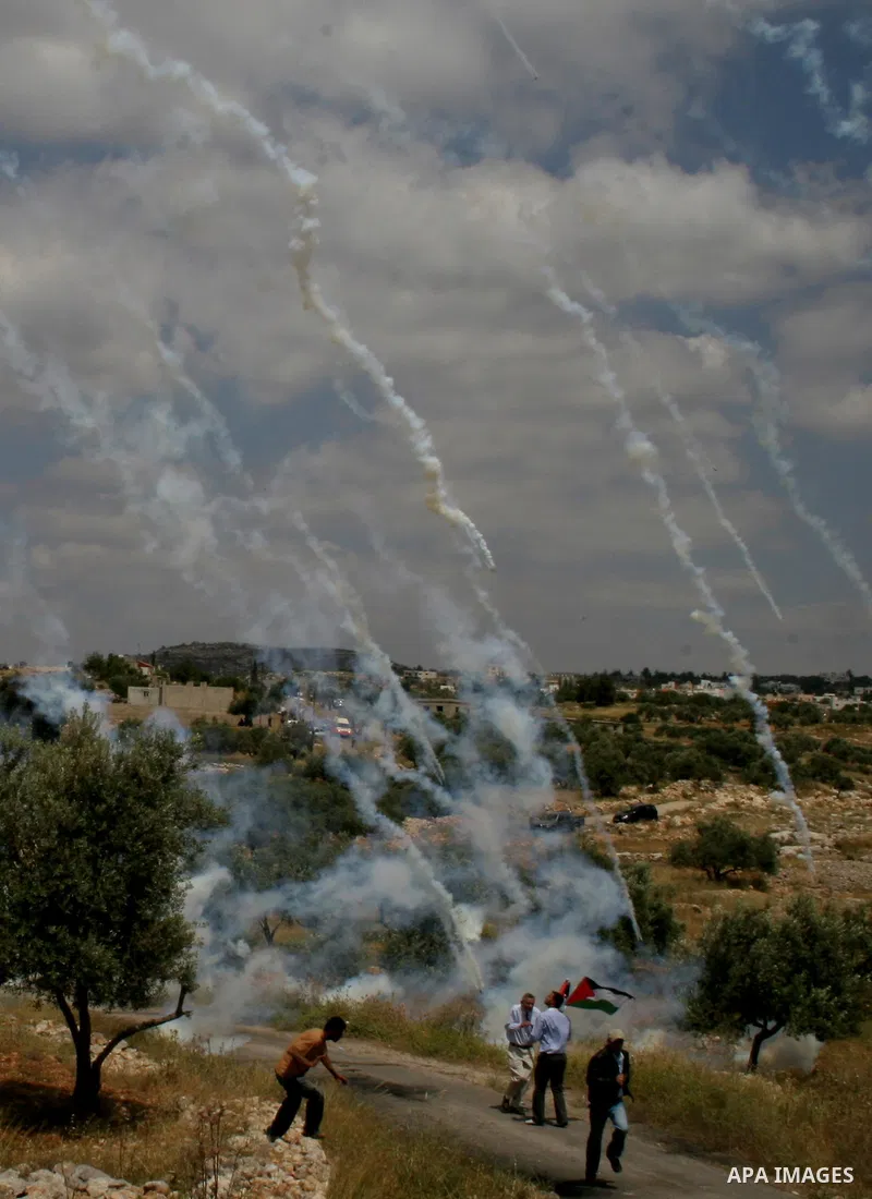 Palestinian demonstrators run for cover as Israeli soldiers fire tear gas during a protest against Israel's controversial separation barrier in the West Bank village of Bilin, near Ramallah, on May 1, 2009.APAIMAGES PHOT...
