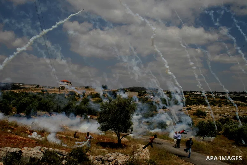 Palestinian demonstrators run for cover as Israeli soldiers fire tear gas during a protest against Israel's controversial separation barrier in the West Bank village of Bilin, near Ramallah, on May 1, 2009.APAIMAGES PHOT...