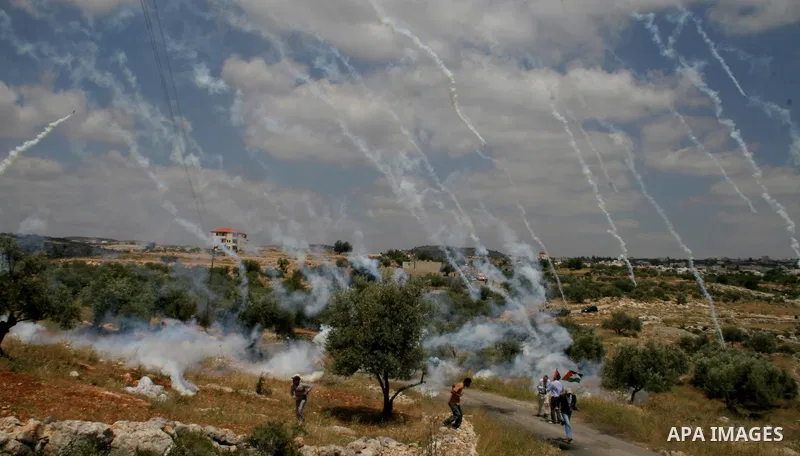 Palestinian demonstrators run for cover as Israeli soldiers fire tear gas during a protest against Israel's controversial separation barrier in the West Bank village of Bilin, near Ramallah, on May 1, 2009.APAIMAGES PHOT...