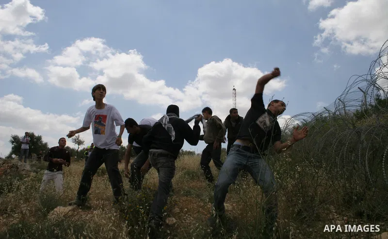 Palestinian activists throw stones at Israeli soldiers during a protest against Israel's controversial separation barrier in the West Bank village of Bilin, near Ramallah, Friday, May 1, 2009.APAIMAGES PHOTO /Issam Rimaw...