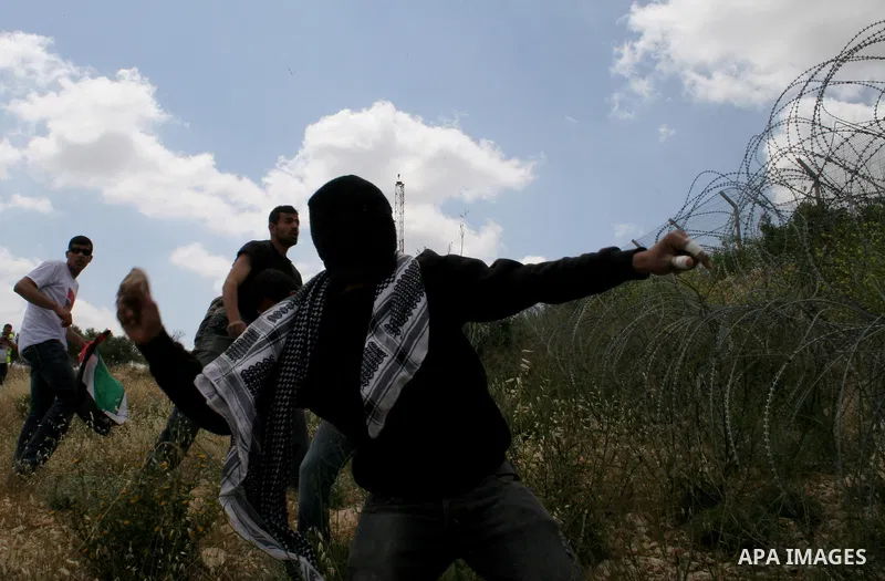 Palestinian activists throw stones at Israeli soldiers during a protest against Israel's controversial separation barrier in the West Bank village of Bilin, near Ramallah, Friday, May 1, 2009.APAIMAGES PHOTO /Issam Rimaw...