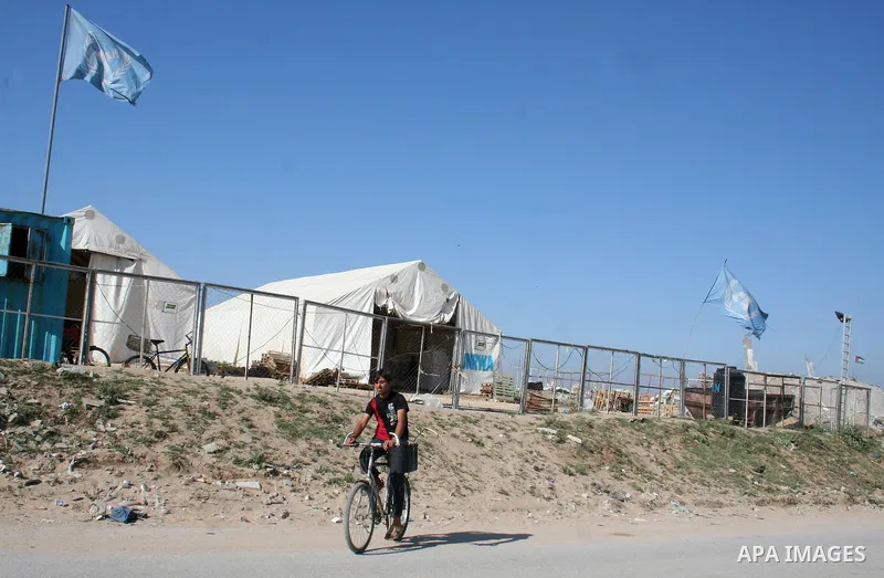 Palestinian stand outside temporary tents for the United Nations Relief and Works Agency (UNRWA) for Palestinian refugees near houses that were destroyed during Israel's 22-day offensive, in Jabalia refugee camp in the n...