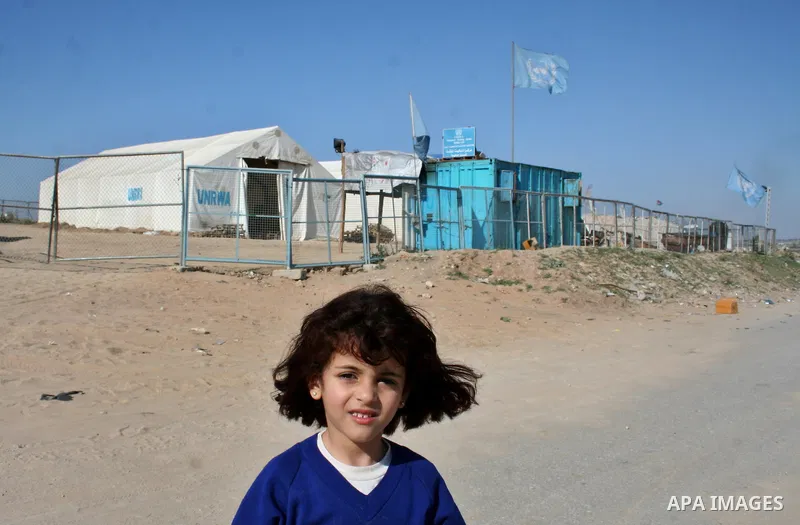 Palestinian children stand outside temporary tents for the United Nations Relief and Works Agency (UNRWA) for Palestinian refugees near houses that were destroyed during Israel's 22-day offensive, in Jabalia refugee camp...