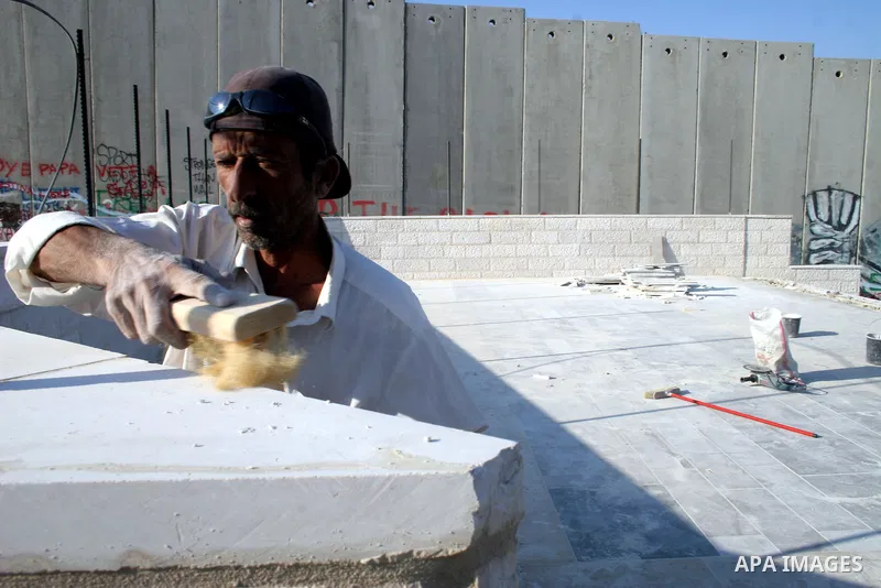 Palestinian labourers put finishing touches on the floor of an amphitheatre being constructed for the expected visit of Pope Benedict XVI, beside the controversial Israeli barrier in Aida refugee camp in the West Bank to...