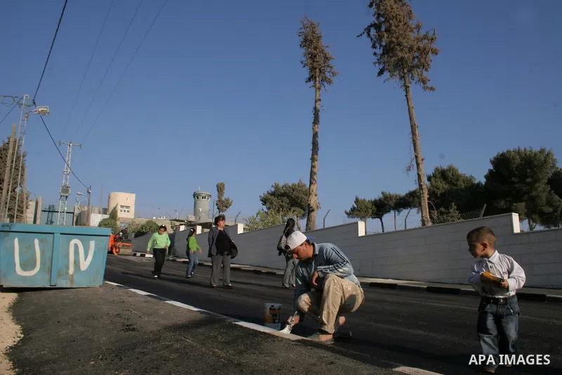 A Palestinian labourer lays down asphalt near an amphitheatre being constructed for the expected visit of Pope Benedict XVI, beside the controversial Israeli barrier in Aida refugee camp in the West Bank town of Bethlehe...