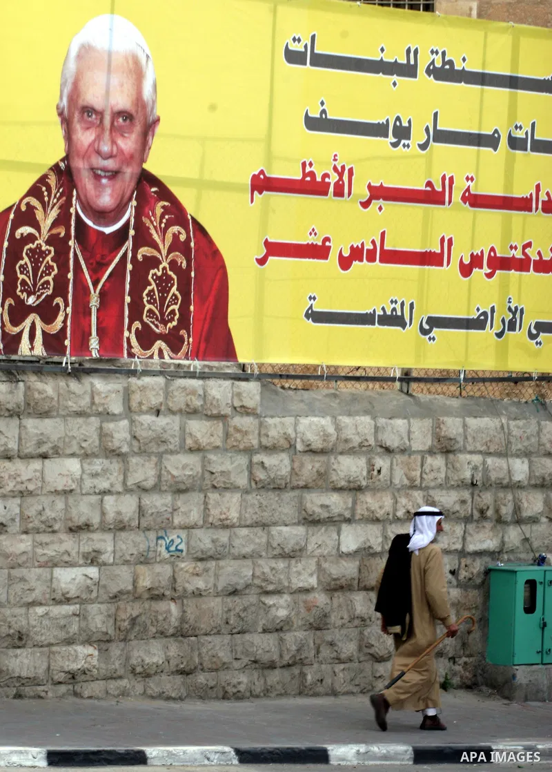 A Palestinian Muslim walks past a banner showing the portrait of Pope Benedict XVI, in the West Bank town of Bethlehem,Monday, May 11, 2009.APAIMAGES PHOTO /Issam rimawi