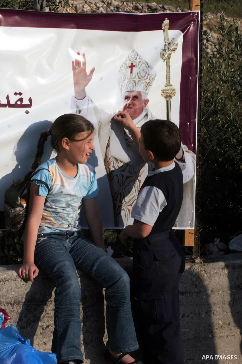 Palestinian children next to a banner showing the image of Pope Benedict XVI, in Bethlehem in the West Bank, monday, May 11, 2009.APAIMAGES PHOTO /Issam rimawi