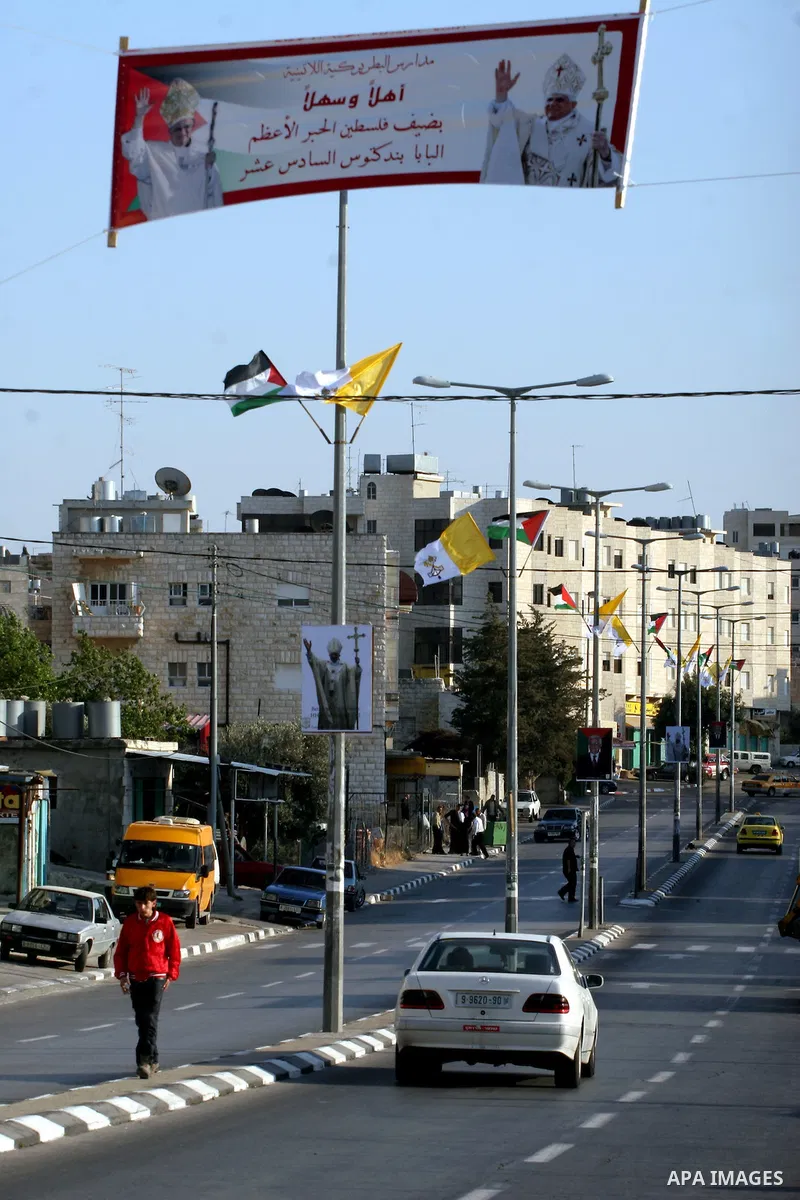 Palestinian child walking down a banner showing the image of Pope Benedict XVI, in Bethlehem in the West Bank, Monday, May 11, 2009.APAIMAGES PHOTO /Issam rimawi