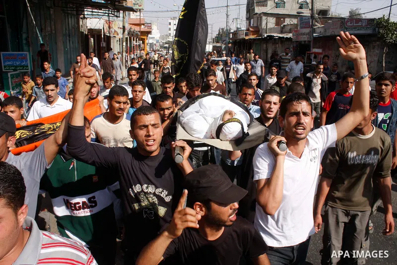 Palestinians carry the body of Abed al-Majeed Salim, 19, a fighter with the Islamic Jihad movement, into a hospital in Rafah in the southern Gaza Strip after he and another militant were killed by Israeli troops on 22 Ma...