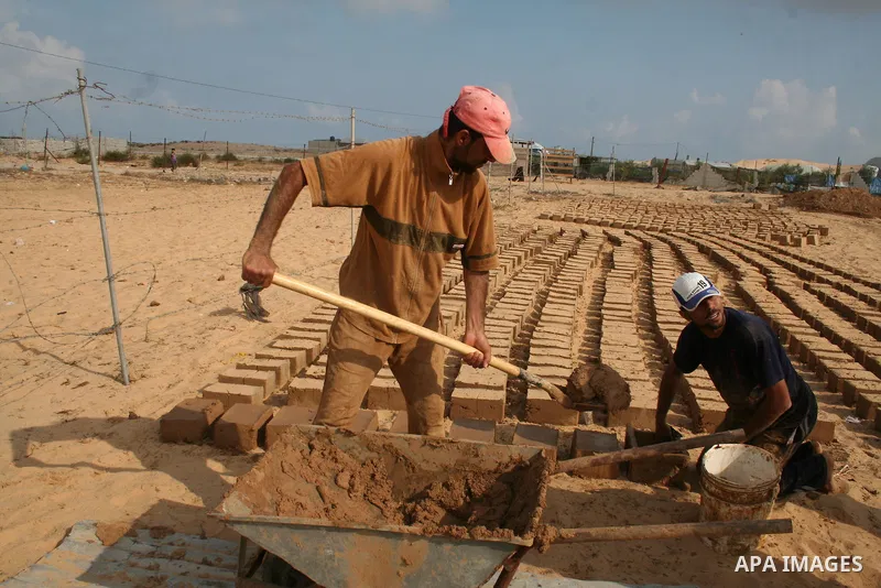 Palestinian workers use mud bricks to build a house in the southern Gaza Strip refugee camp of Rafah on May 24 2009. APAIMAGES PHOTO / Ashraf Amra